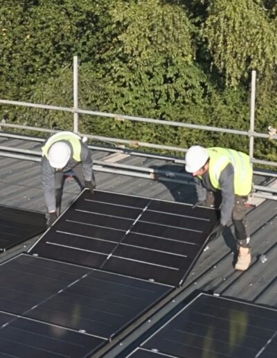 Solar panels being installed by 2 workers on the roof of Stychbrook Leisure Centre